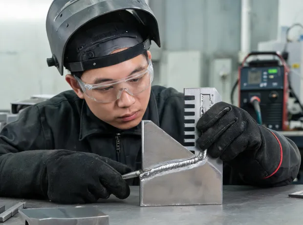 Fabricator inspecting a MIG bead